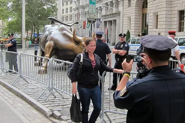 An officer takes a picture of the bull for a tourist on the very first day of OWS